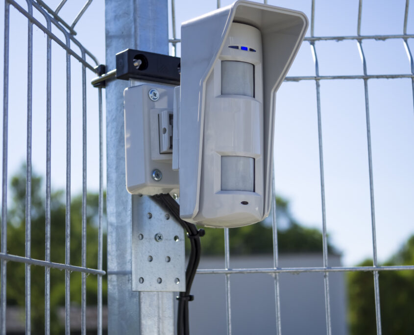 Motion sensor on open protected area. Installed on the fence and connected to the security system with wires. Multifunctional microwave detector. Outdoor guard. Concept of personal or object security.